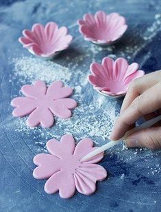 a person is decorating pink flowers on a blue surface with powder and a brush