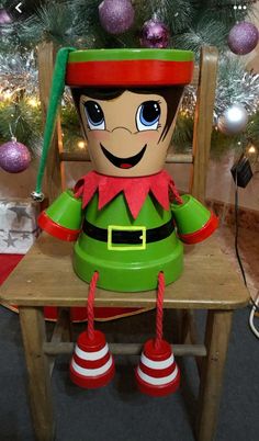 an inflatable elf sitting on a chair next to a christmas tree