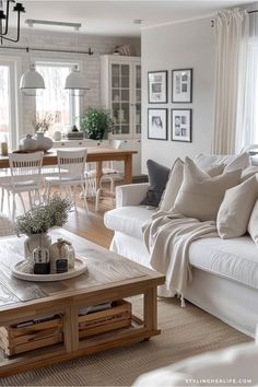 a living room filled with white furniture and lots of pillows on top of the couches