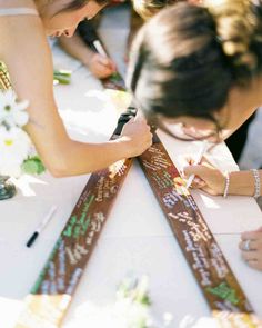 the bride and groom are signing their wedding vows at the reception table with flowers on it