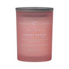 a candle that is sitting on top of a white surface with the words peony apple written