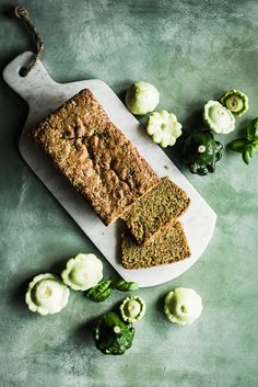 a loaf of bread sitting on top of a cutting board next to cauliflower