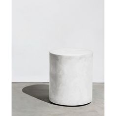 a white round table sitting on top of a cement floor next to a white wall