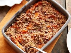 a casserole dish with meat and vegetables in it on a wooden table next to plates