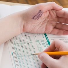 a person holding a pencil in their left hand and writing on paper next to a calculator