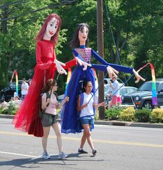 two women and one child are walking down the street with clowns on their heads