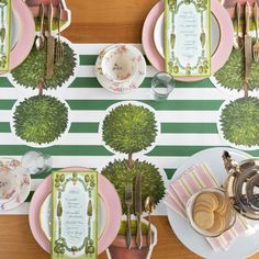 the table is set with pink and green plates, silverware, and place settings