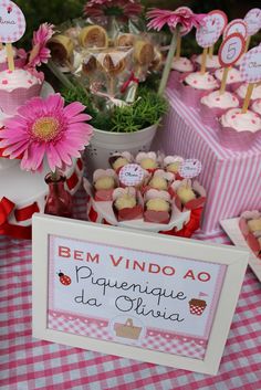 a table topped with lots of cupcakes next to a pink and white checkered table cloth