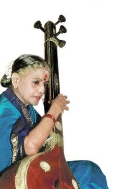 a woman sitting on top of a wooden chair holding a musical instrument in her hand