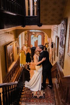 a bride and groom are kissing on the stairs at their wedding reception in an old building