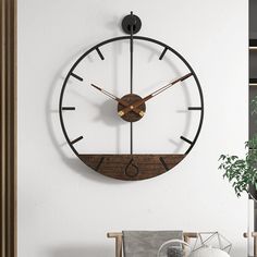 a large clock mounted to the side of a wall next to a potted plant