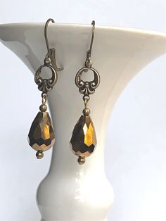 Antique bronze earrings feature brass Fleur de Lis connectors with vintage bronze fire polished faceted glass drops. Antique brass lever back earwires complete these brass Fleur de Lis earrings and they would be ideal for gift giving or anniversary gift, gift for mom, gift for girlfriend, or special occasion jewelry. We are proud to be part of the sustainable fashion movement by repurposing jewelry and components which would otherwise be discarded. We believe our company is responsibly reducing Bronze Metal Teardrop Earrings For Gift, Bronze Dangle Teardrop Earrings For Gift, Bronze French Hook Earrings As Gift, Vintage Handmade Gold Teardrop Earrings, Teardrop Brass Crystal Earrings As Gift, Vintage Gold Earrings With Lever Back, Teardrop Brass Crystal Earrings For Gifts, Bronze Teardrop Earrings With French Hook, Bronze Nickel-free Drop Earrings