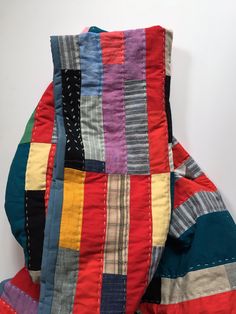 a multicolored patchwork quilt on the back of a chair with white background