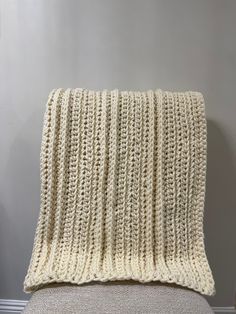 a white knitted blanket sitting on top of a chair