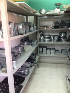 an industrial kitchen with lots of pots and pans on shelving in the corner