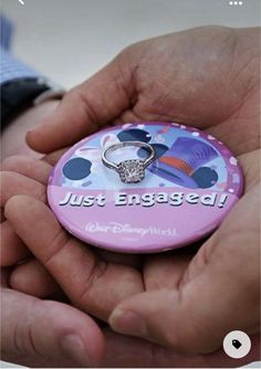 a person holding a button with a ring on it that says just engaged in front of them