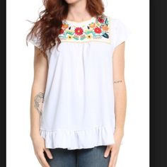 This embroidered top is full of life with it's bright colors! it has an easy going, relaxed fit to stay light and cheery with the complementing bottom ruffle. Bohemian Tops With Embroidered Hem And Relaxed Fit, Bohemian Tops With Embroidered Hem In Relaxed Fit, Spring Crew Neck Top With Embroidered Neckline, Spring Crew Neck Blouse With Embroidered Hem, Spring Embroidered Neckline Crew Neck Top, Casual Embroidered Short Sleeve Top For Spring, Casual Embroidered Top With Relaxed Fit For Spring, Casual Floral Embroidered Top For Summer, Summer Ruffled Relaxed Fit T-shirt