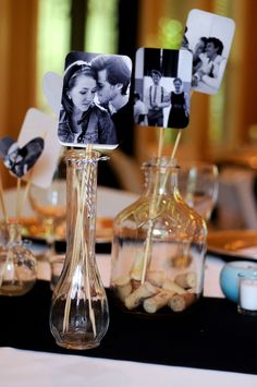 a table topped with vases filled with flowers and pictures on top of each other