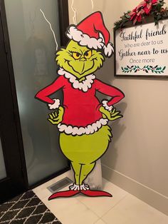 the grinch is standing in front of a christmas sign