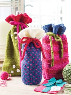 three knitted bags sitting on top of a table next to yarn balls and scissors