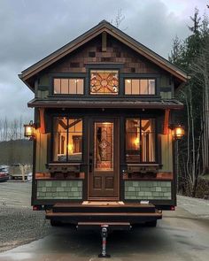 a tiny house is sitting in the middle of a parking lot with its lights on