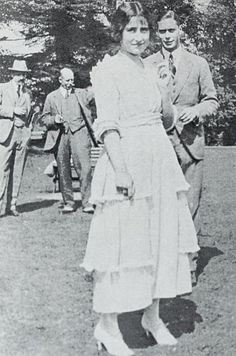 an old black and white photo of a woman in a dress standing next to two men