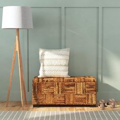 a wooden trunk sitting next to a lamp on top of a hard wood floor in front of a green wall