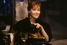 a woman sitting at a table with a plate and wine glass in front of her