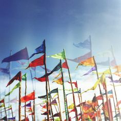 many colorful flags blowing in the wind on a sunny day