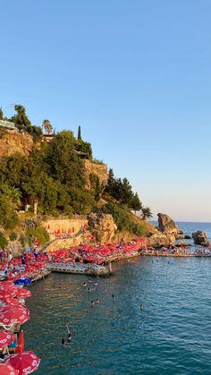 the beach is crowded with umbrellas and people swimming in the blue water near an island