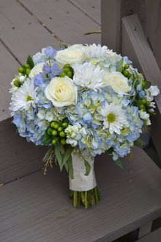 a bouquet of white and blue flowers on a bench