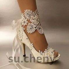 a woman's white high heeled shoe with lace and flowers on the side