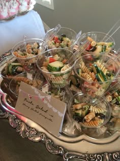 a tray filled with lots of different types of pasta and veggies in plastic cups