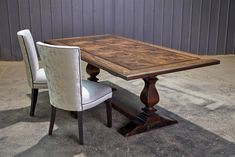 a wooden table with two white chairs and a gray wall in the backround