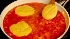 a white bowl filled with soup and tortilla chips on top of it next to a wooden spoon