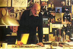 a man standing in front of a desk with many pictures on the wall