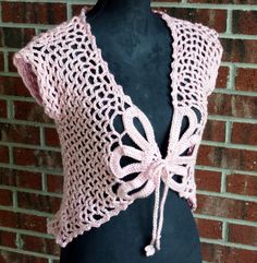 a pink crocheted shawl on a mannequin torso with a brick wall in the background