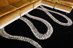 a black and white rug with snake skin on the floor next to a brown couch