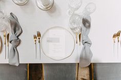 the table is set with silver and gold place settings, napkins, and forks