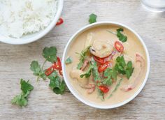 a white bowl filled with food next to rice and cilantro