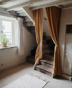 a room with some stairs and curtains on the windowsill