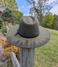 This hand burnt olive green wide brim fedora makes a perfect addition to any nature lover's wardrobe. I burnt pine trees on the back brim of the hat. Around the entire crown of the hat I intricately burned and shaded mountains and pine trees by hand with a pyrography machine. The design is original and completely free-handed. For a finishing touch, I added faux stitch marks on the crown and brim of the hat. The hat has a faux leather black belt hat band. Hat Materials: polyester/cotton Hat circu Rustic Felt Hat With Flat Brim For Outdoor, Rustic Brimmed Felt Hat For Outdoor, Rustic Flat Brim Felt Hat For Outdoor, Green Curved Brim Hat For Outdoor, Artisan Style Fedora With Flat Brim For Outdoor, Khaki Fedora Sun Hat For Outdoor, Adjustable Green Fedora For Country Events, Rustic Wide Brim Hat For Outdoor, Country Style Hat With Flat Crown For Outdoor