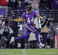 a football player running with the ball in his hand and people watching from the stands