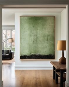 an empty room with a large painting hanging on the wall and a wooden table in front of it