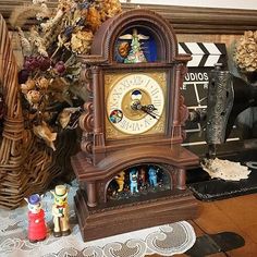 a clock sitting on top of a wooden table next to flowers and other decorations in front of a mirror