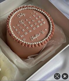 a pink cake with white frosting and writing on it in a box next to other items