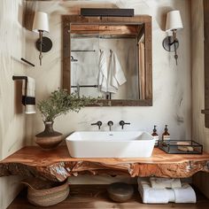 a bathroom sink sitting under a mirror on top of a wooden counter next to a lamp