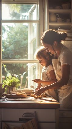 a woman and child are preparing food on a counter top in front of a window