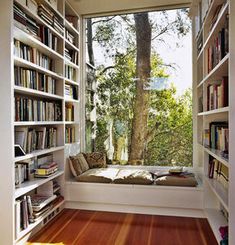 a window seat in the corner of a room with bookshelves full of books