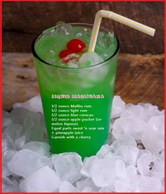 a green drink sitting on top of ice with a straw in it's mouth